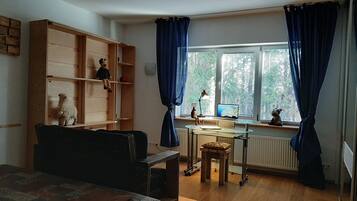 Una stanza con un letto, una scrivania con un computer, una libreria e una finestra con tende.
