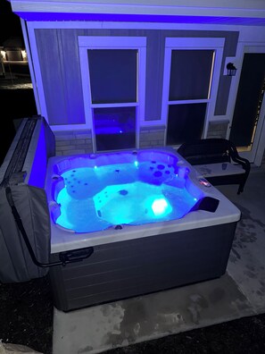 A hot tub with a control panel and a chair, set against a house with a screened porch. - Red Sand Ridge. The best place to enjoy your vacation in Moab! (Moab)