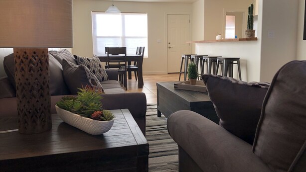 A modern living room with a sofa, coffee table, and decorative items. There is a dining area with a table and chairs in the background. - Red Sand Ridge. The best place to enjoy your vacation in Moab! (Moab)