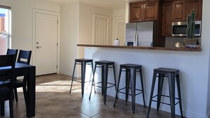 A kitchen with wooden cabinets, a refrigerator, a microwave, and a bar area with stools. - Red Sand Ridge. The best place to enjoy your vacation in Moab! (Moab)