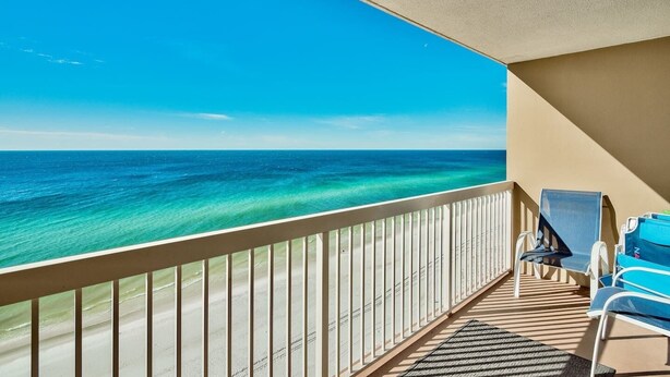 Een balkon met uitzicht op de oceaan, een stoel en een klein tafeltje.