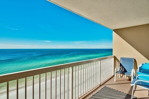A balcony with a view of the ocean, a chair, and a small table. - Majestic Ocean Views, Oceanfront Condo, Renovated (Destin)