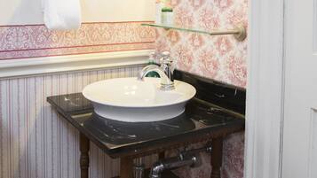 A bathroom with a white sink, wooden vanity, and a mirror with a gold frame.