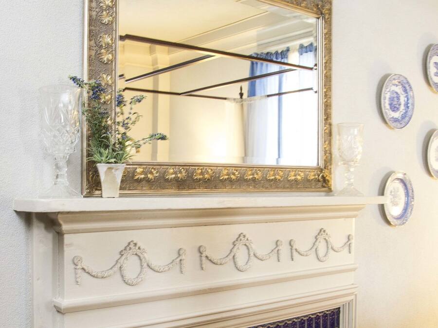 Un caminetto con rivestimento in piastrelle, uno specchio sopra e piatti decorativi appesi al muro.