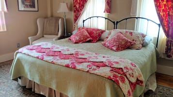 Un dormitorio con cama, una silla, una lámpara y cortinas.