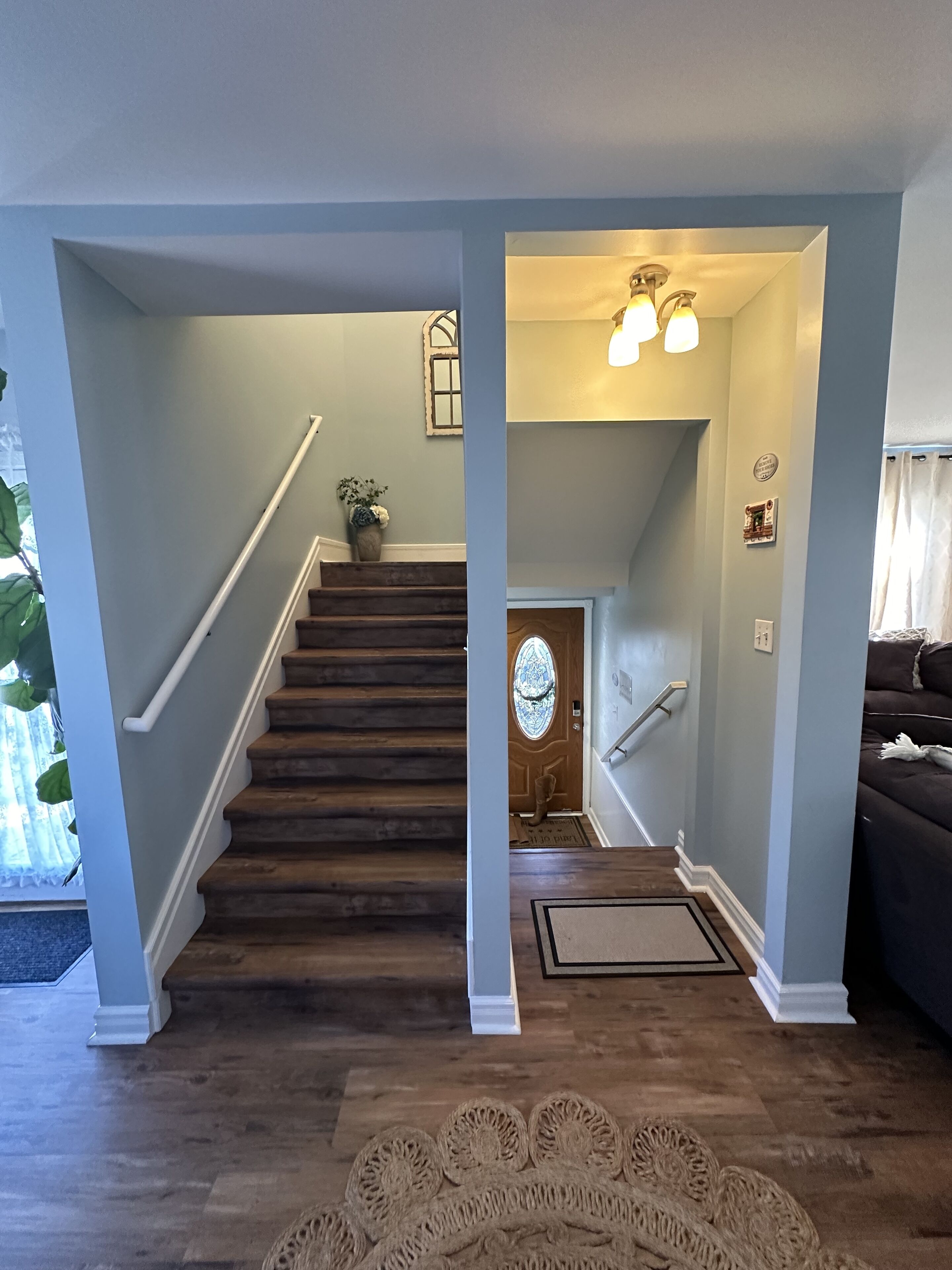 A staircase with wooden steps and white railings, leading to a door with a decorative glass window.