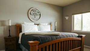 Een slaapkamer met een houten bed, twee nachtkastjes, een wandlamp en een raam met uitzicht.