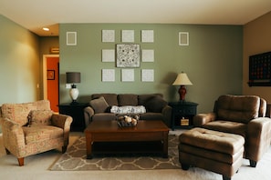 A living room with a sofa, two armchairs, a coffee table, and decorative wall art. - Relax in beautiful mountain serenity while planning your local adventures. (Coeur d' Alene)
