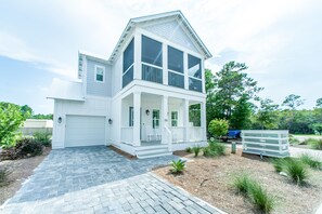 Une maison à deux étages avec un porche à l’avant, un garage et une allée.