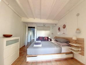 A bedroom with a bed, bedside tables, a dresser, and a hallway leading to another room.