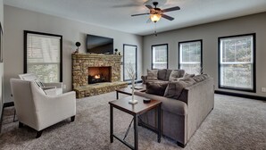 A living room with a fireplace, a sofa, a chair, and a ceiling fan.