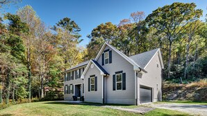 A two-story house with a garage, surrounded by a well-maintained lawn and trees.