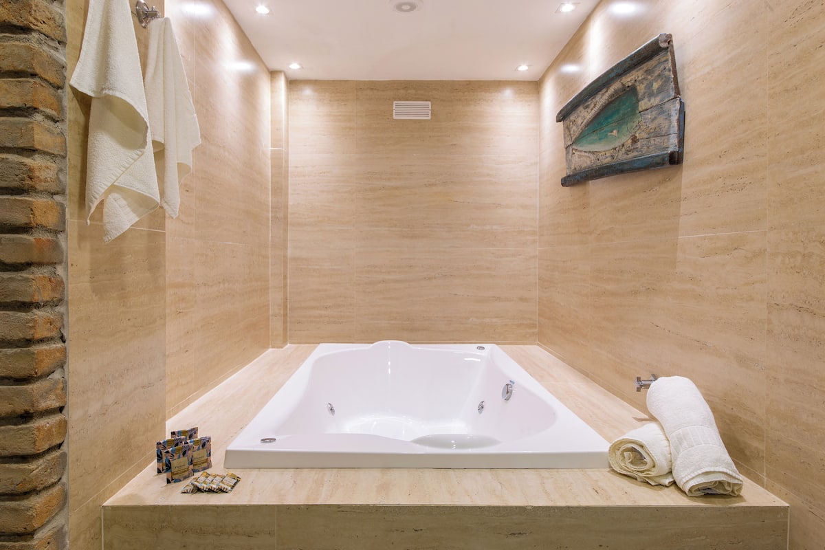 Un baño moderno con una bañera grande, un perchero y un adorno en la pared.