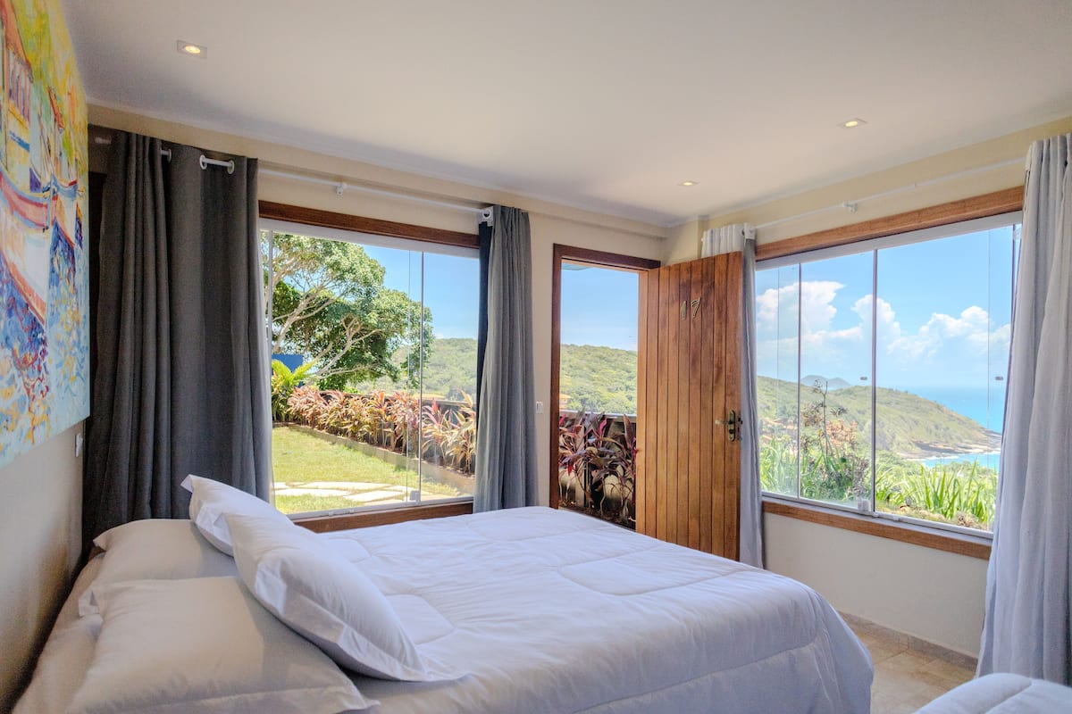 Un dormitorio con dos camas, ventanas amplias y vista al océano.