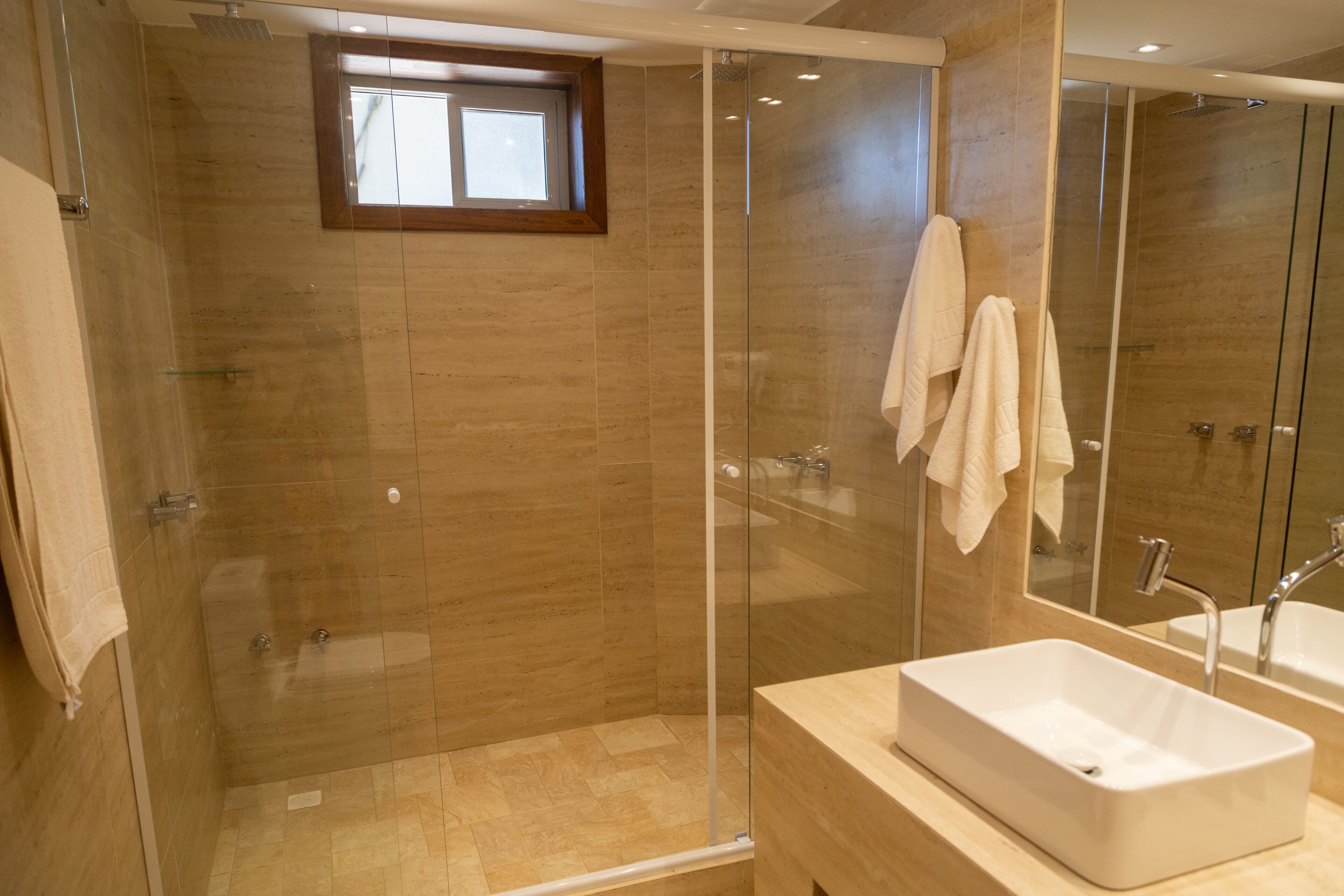 A modern bathroom with a glass-enclosed shower, a large mirror, and a white sink.