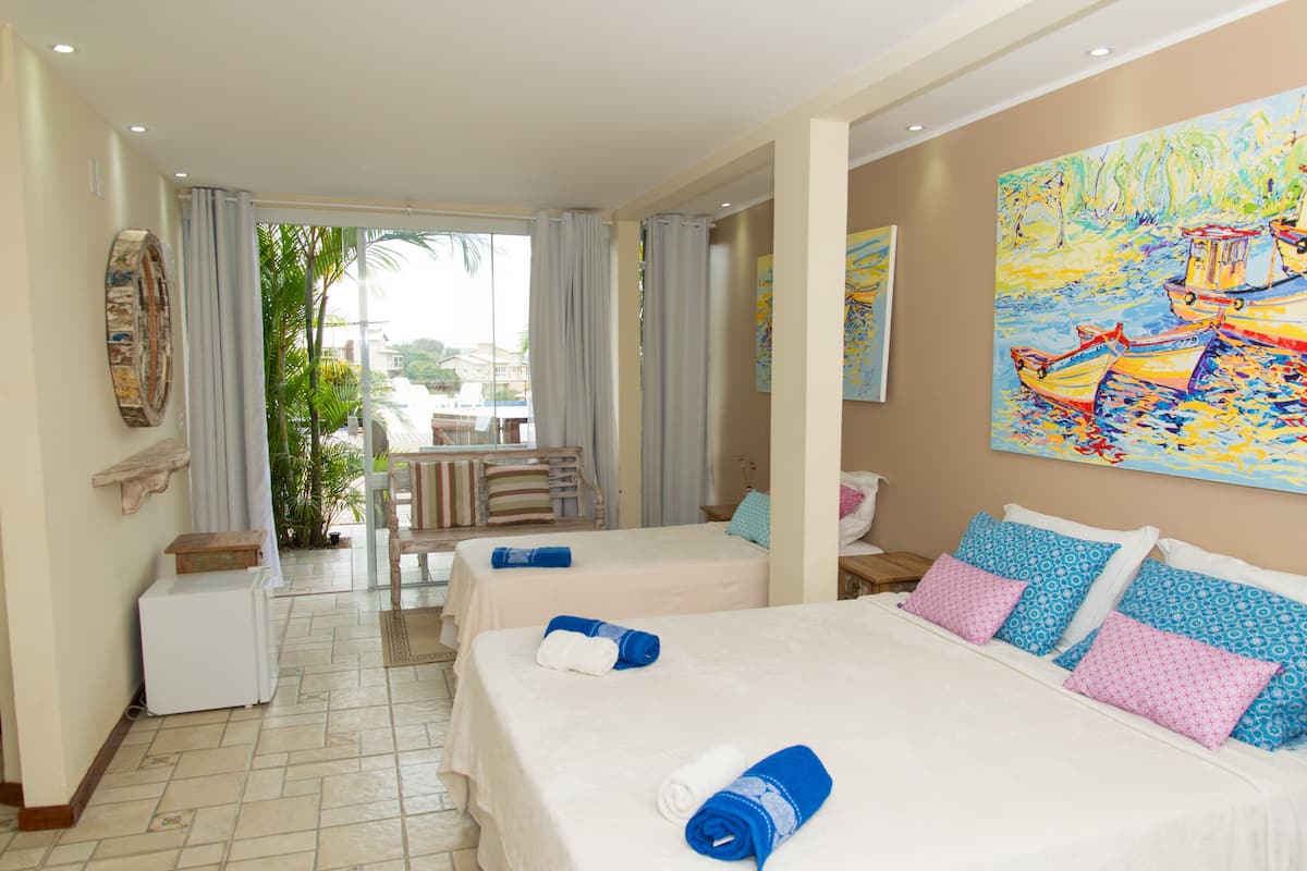 Habitación de hotel con dos camas, zona de comedor y vistas al exterior.