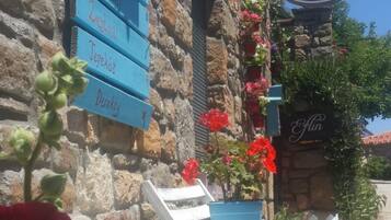 Un edificio de piedra con un letrero que dice 'Elin Butik Hotel' y asientos exteriores con sillas azules y una mesa.