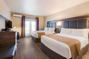 Habitación de hotel con dos camas, un escritorio, un televisor y una ventana con cortinas.