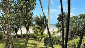 Un área con césped, palmeras y vista a la playa.