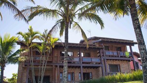 Un edificio de varios pisos con fachada de ladrillo, balcones y palmeras.