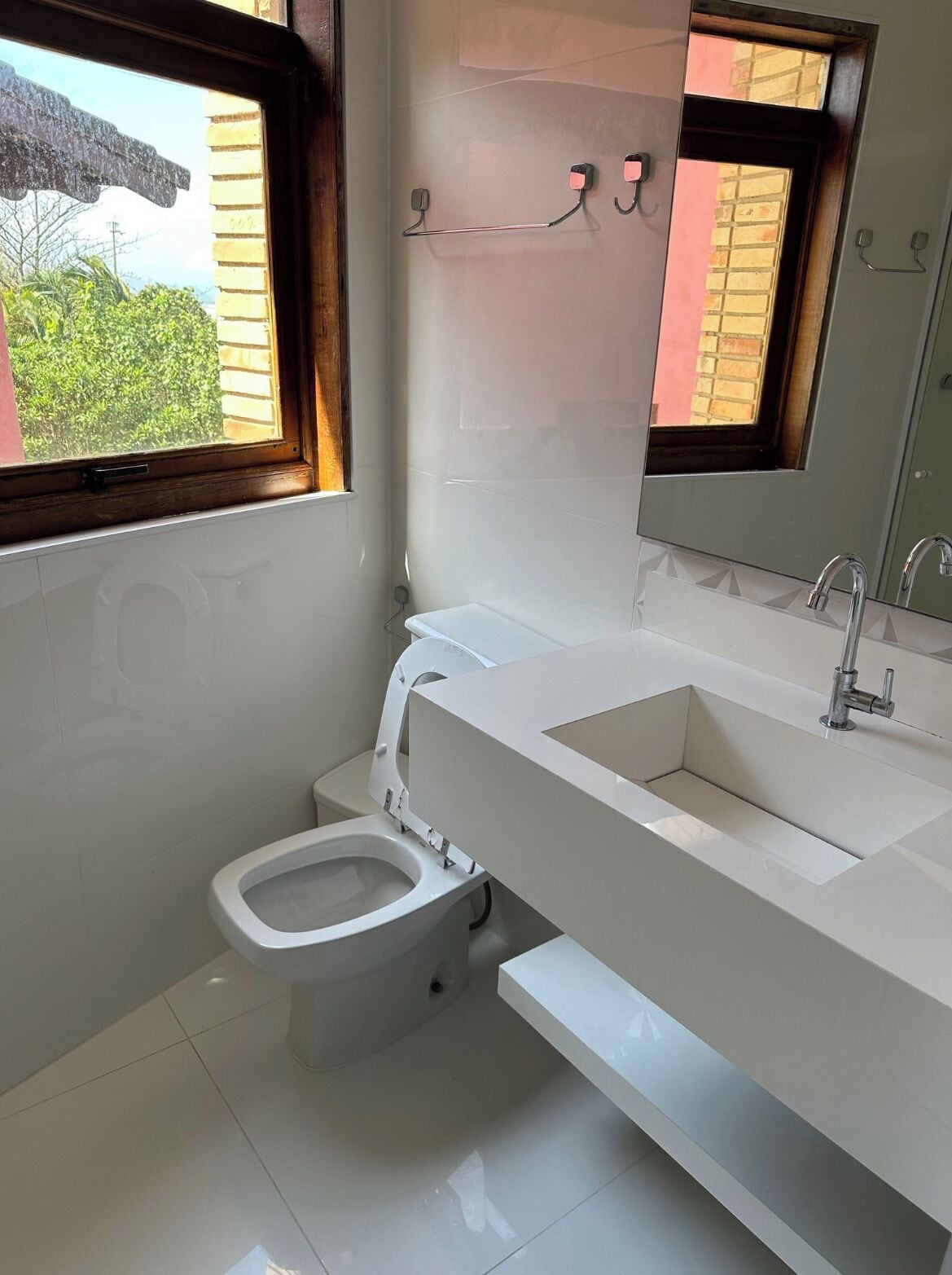 A modern bathroom with a toilet, sink, and window.