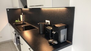 A modern kitchen with a black countertop, a coffee maker, a toaster, and a kettle.