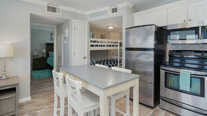 Una cocina con armarios blancos, un refrigerador de acero inoxidable y un horno doble.