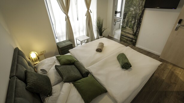 A modern hotel room with a large bed, a sofa, a small table, and a TV mounted on the wall. - Boutique accommodation Shappy (Zagreb)