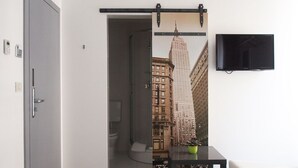 A room with a sliding door leading to a bathroom, a flat-screen TV mounted on the wall, and a small table with a plant. - Boutique accommodation Shappy (Zagreb)