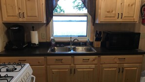 A kitchen with wooden cabinets, a gas stove, a sink, a coffee maker, and a microwave.