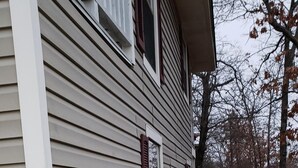 A wooden deck leading to a house with white siding and red shutters.