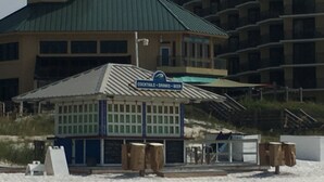 Un edificio frente a la playa con un letrero que indica que ofrece cócteles, bebidas y cerveza.