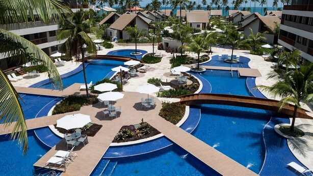 Un complexe hôtelier doté de plusieurs piscines, de palmiers et offrant une vue sur la plage.