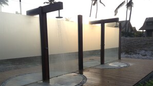 Une terrasse en bois agrémentée de deux éléments décoratifs à base d’eau, d’une bordure en pierre et d’un palmier en arrière-plan.