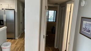 Ein Flur mit einem Edelstahlkühlschrank, einer Mülltonne und einem gerahmten Bild an der Wand.