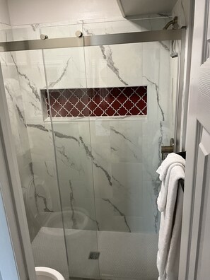 A shower with a glass door, marble walls, and a towel rack. - Dunescape with 3 ensuite full bathrooms. Private beach access chairs included! (Atlantic Beach)