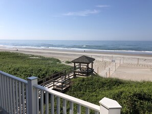 Une vue sur la plage avec un kiosque en bois et une balustrade blanche.