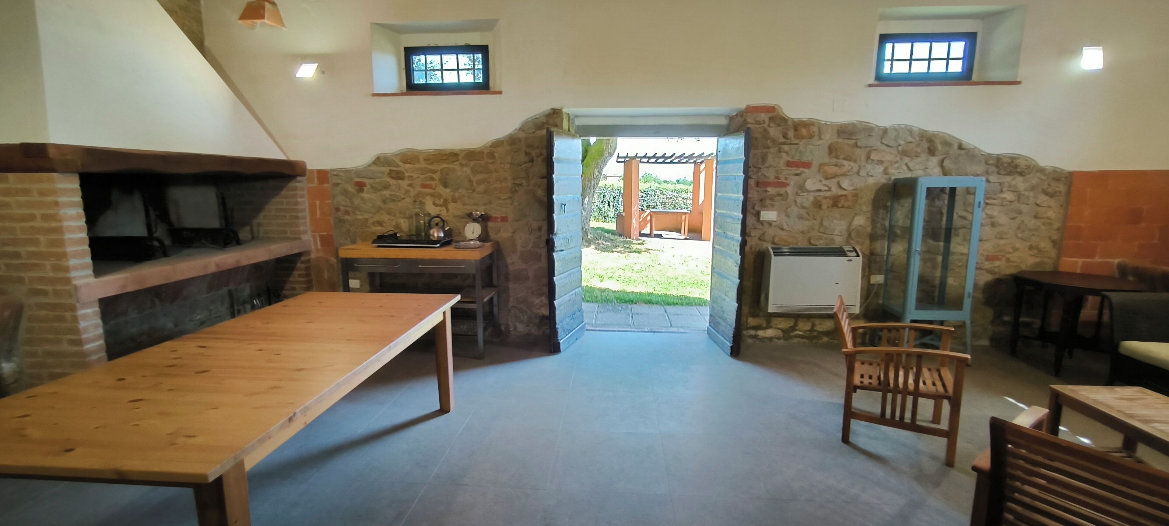 Un intérieur rustique avec un mur en pierre, des meubles en bois et une vue sur un patio extérieur.