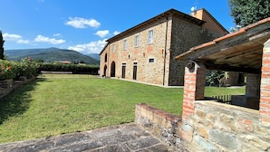 A stone building with a garden and a view of mountains.