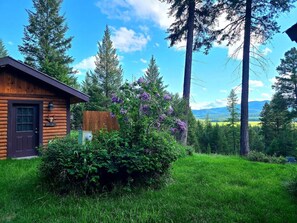 A log cabin with a dark door and a small porch area. - KM Ranch Hideaway Cabin (Whitefish)