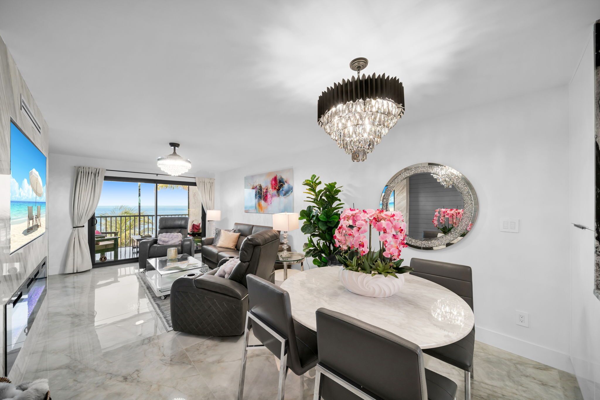 A modern living room with a marble floor, a dining table with chairs, a chandelier, and a large mirror on the wall.