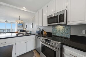 A modern kitchen with white cabinets, a stainless steel stove, and a microwave.