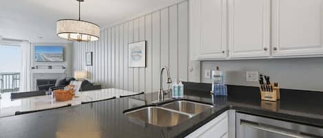Une cuisine moderne avec un plan de travail noir, des appareils en acier inoxydable et des meubles blancs.