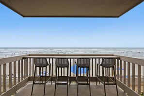 Un balcon avec quatre chaises donnant sur une plage.