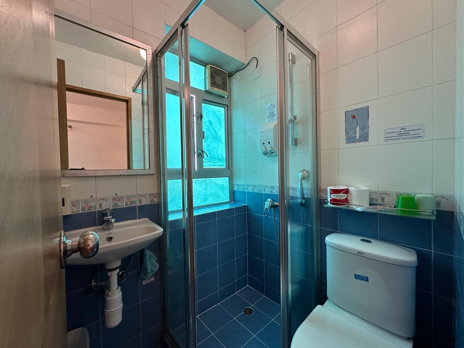 A bathroom with a glass-enclosed shower, a sink, and a toilet.