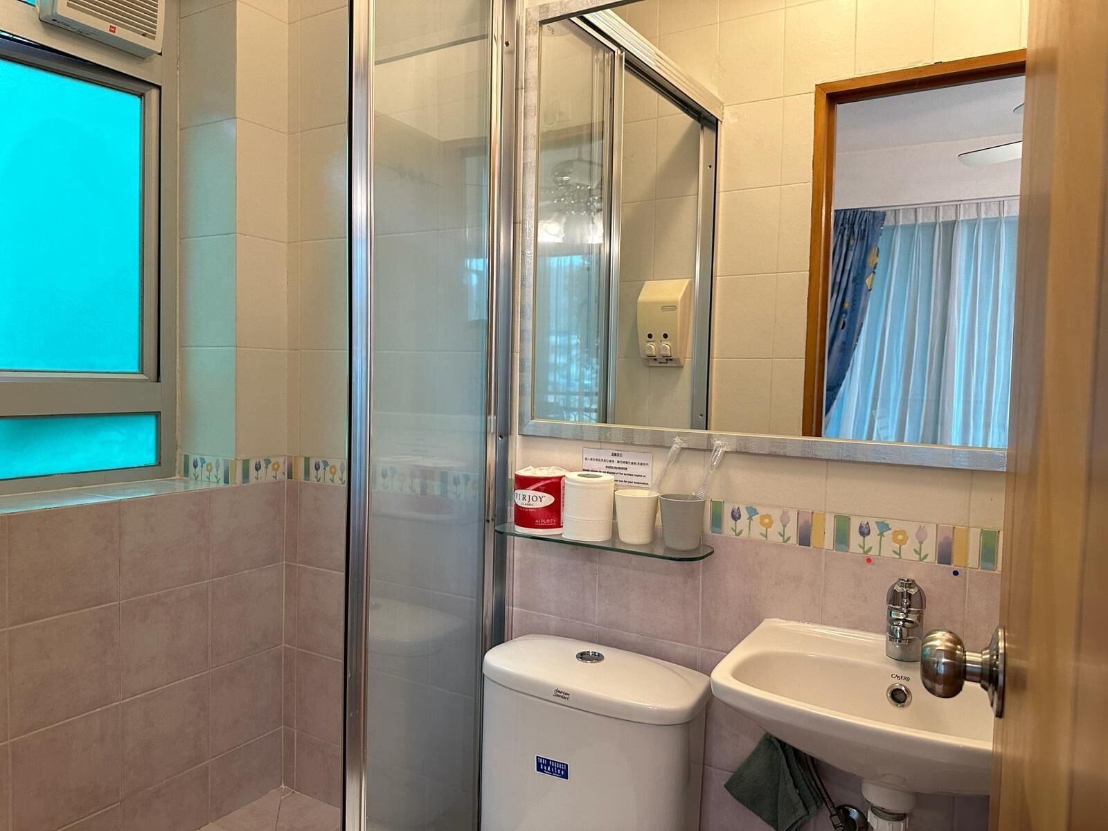 Een badkamer met een douchecabine van glas, toilet, wastafel en spiegel.