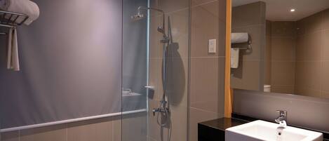 A modern bathroom with a glass-enclosed shower, a white sink, and a towel rack.