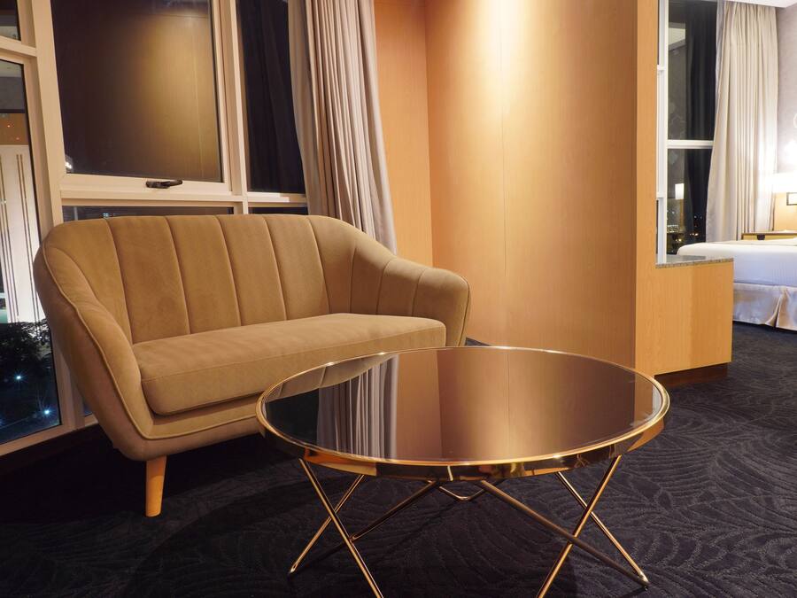 Camera d'albergo con divano, tavolino in vetro, un letto e vista sulla città di notte.