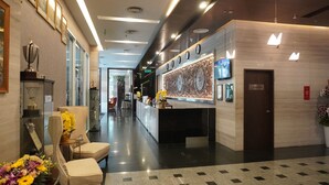 A hotel reception area with a modern design, featuring a reception desk, seating area, and decorative elements like trophies and flowers. - Paya Bunga Hotel Terengganu (Kuala Terengganu)