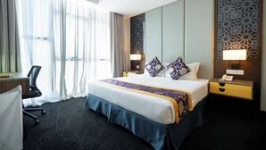 A hotel room with a large bed, a desk, a chair, and a nightstand with a lamp. - Paya Bunga Hotel Terengganu (Kuala Terengganu)